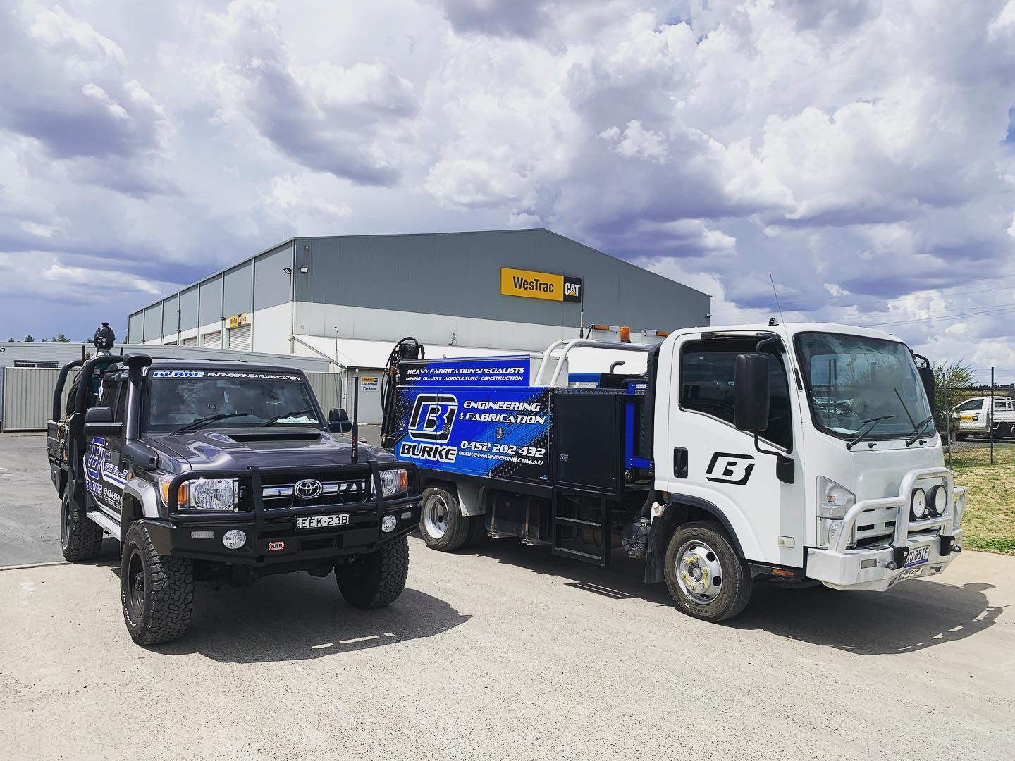 Two engineering service trucks outside a factory.