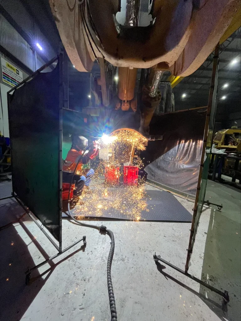 Welder working with sparks in industrial workshop.