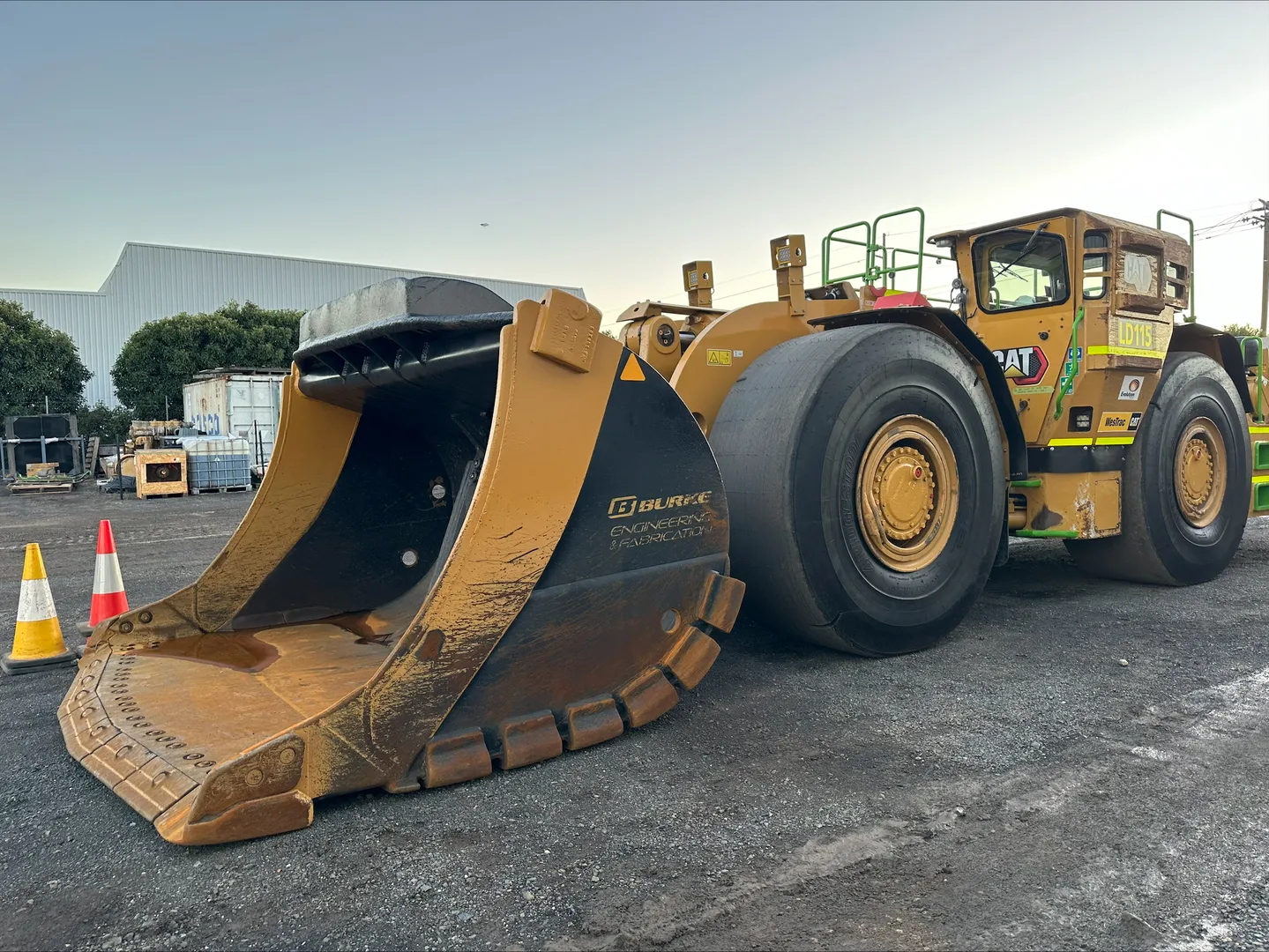 Large yellow mining loader in industrial yard.