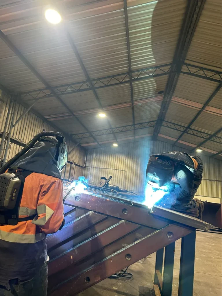 Workers welding metal in industrial workshop.